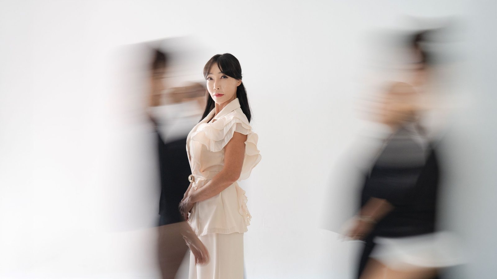 흐르는 배경 속에 서 있는 크림 팬츠 차림 — 김스튜디오
