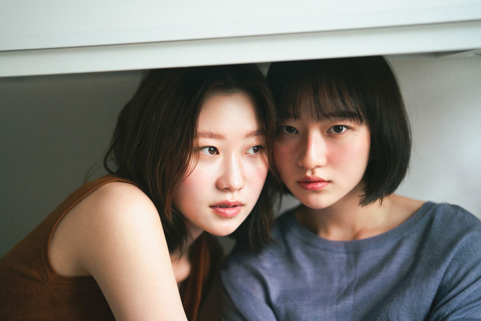 선반 아래 나란히 앉아 카메라를 보는 두 사람 — 김스튜디오