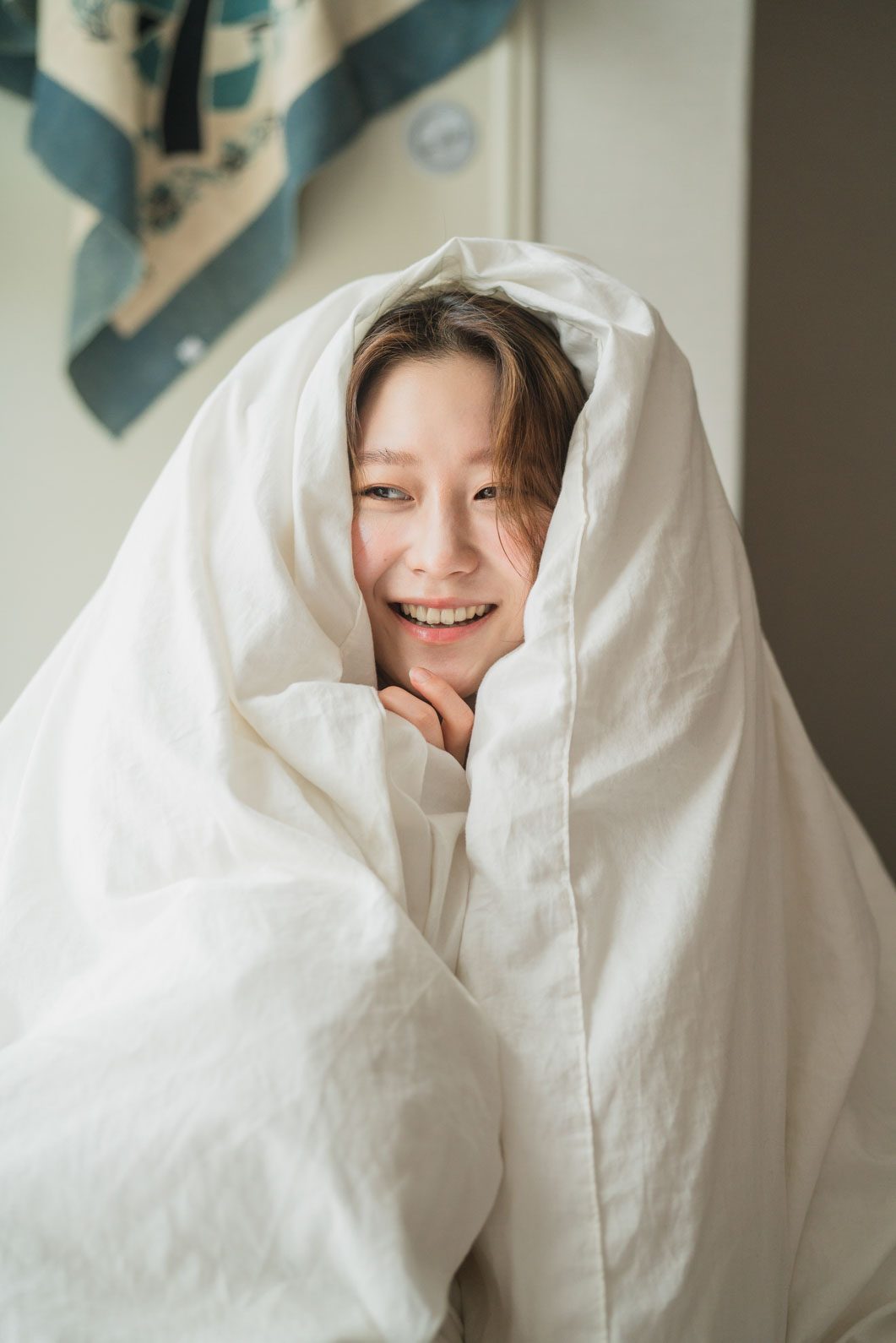 이불을 머리까지 덮고 웃는 컷 — 김스튜디오